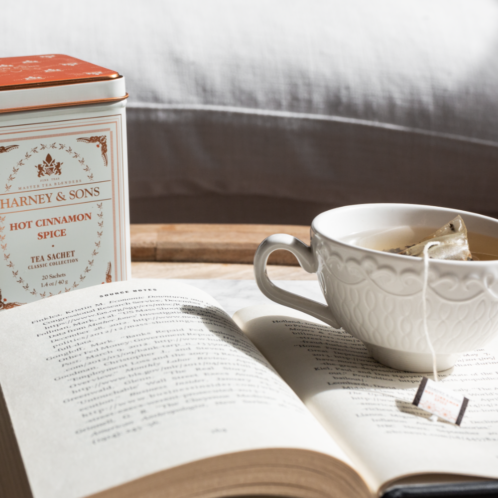 A white teacup and a tin of loose tea on a linen-covered table